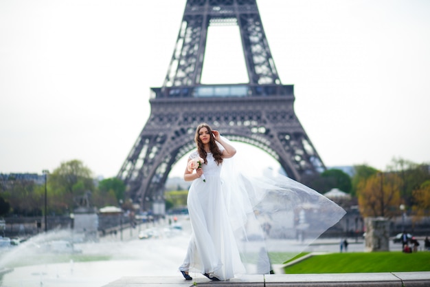 Noiva linda num vestido de noiva rico gira na praça antes da Torre Eiffel