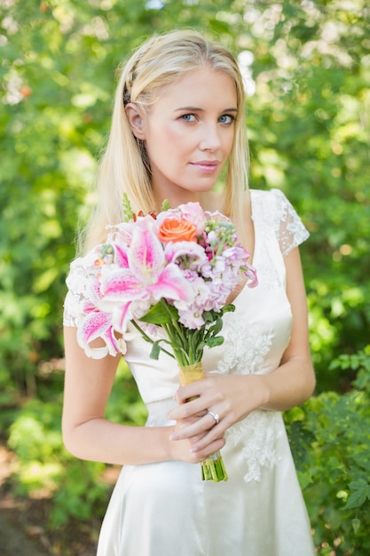 Noiva loira segurando bouquet sorrindo para a câmera