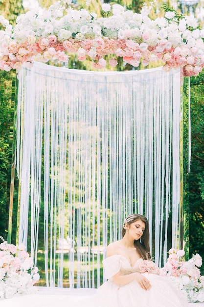 Noiva perto do arco do casamento com flores