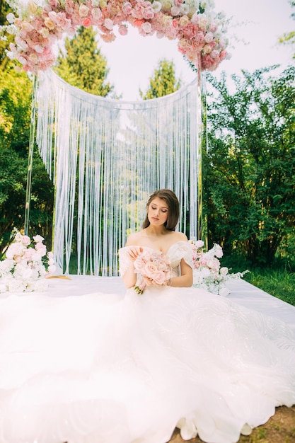 Noiva perto do arco do casamento com flores