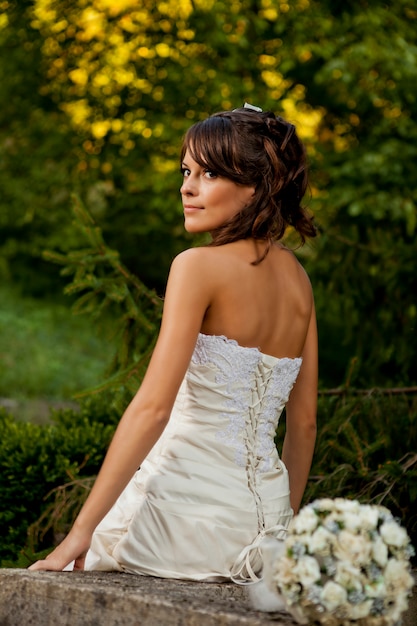 Noiva posando no jardim com um vestido de noiva branco