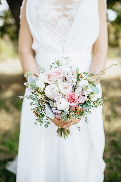 Noiva segurando buquê de casamento com flores brancas e rosa