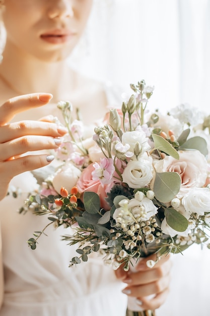 Noiva segurando buquê de casamento com flores brancas e rosa