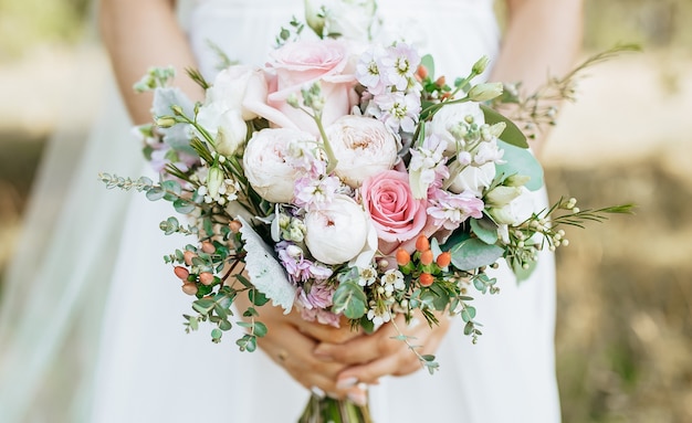 Noiva segurando buquê de casamento com flores brancas e rosa