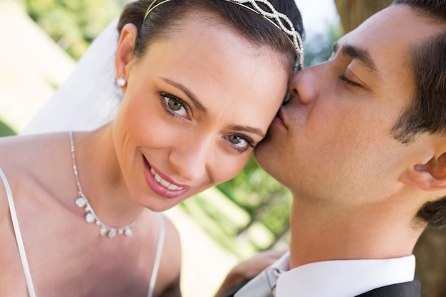 Noiva sendo beijada pelo noivo no jardim