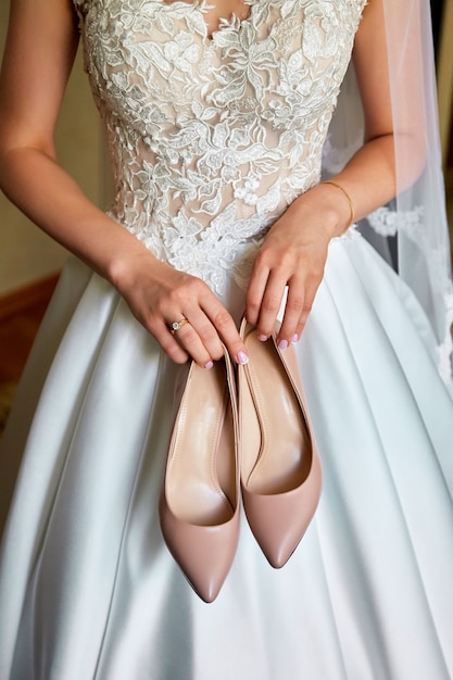 Foto noiva tem os sapatos de casamento nas mãos