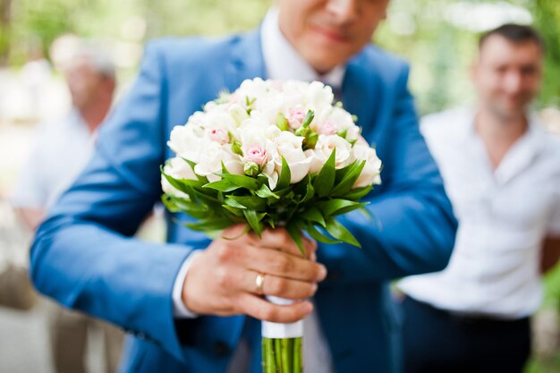 Noivo de terno azul com buquê de casamento