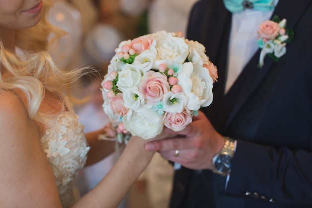 Noivo de terno dá à noiva um buquê de casamento branco e pêssego