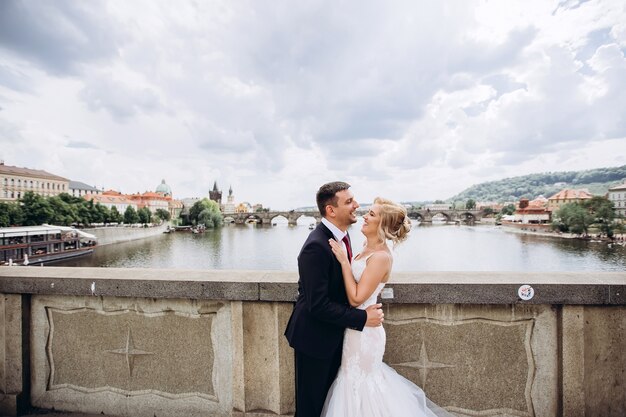 Noivo e noiva caminham na ponte carlos