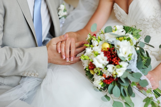 Noivo e noiva de mãos dadas com alianças