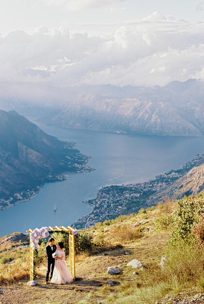 Noivo e noiva no arco do casamento na montanha acima da baía de kotor