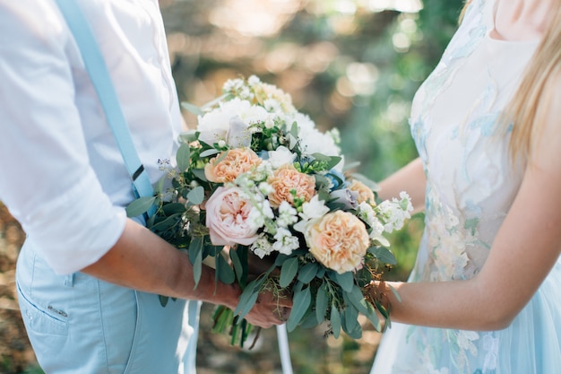 Noivo e noiva segurando o buquê de casamento juntos