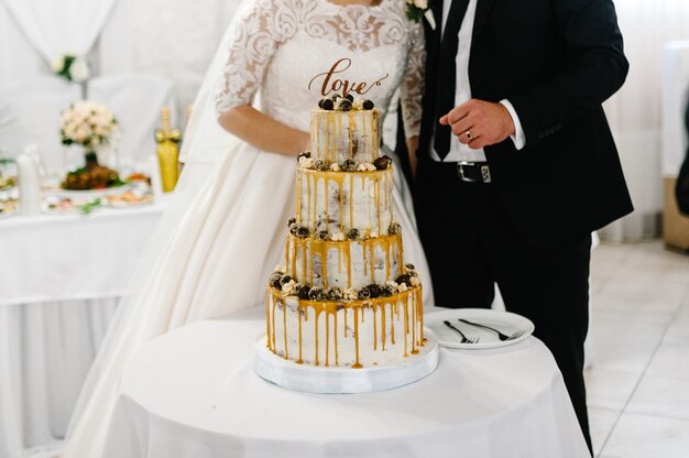 Noivo e noivos cortados cortando seu bolo de casamento rústico