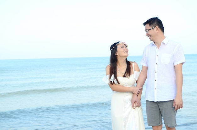 Noivos asiáticos em uma praia tropical. Conceito de casamento e lua de mel.