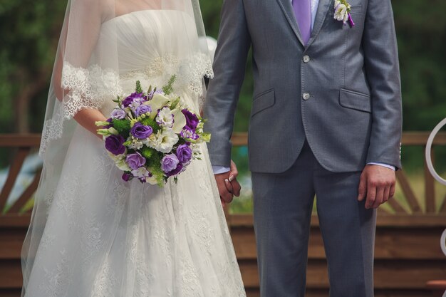 noivos de mãos dadas no dia ensolarado do casamento.