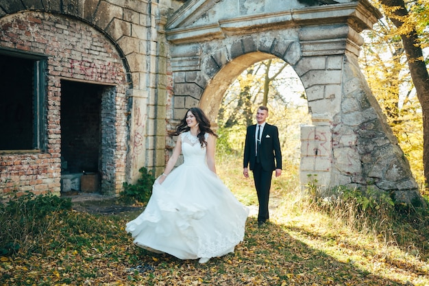 Noivos felizes e apaixonados caminham pelo parque de outono no dia do casamento