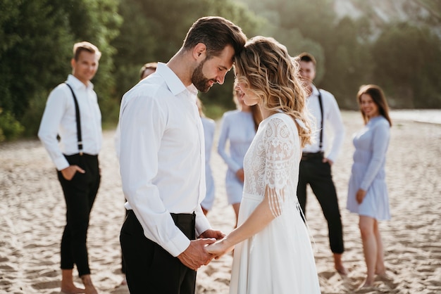 Noivos lindos se casando com convidados em uma praia