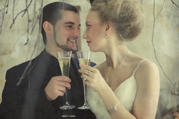 noivos segurando copos com champanhe no quarto vintage