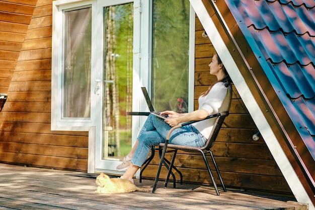 Nómada digital con computadora portátil en la terraza de una pequeña casa de madera