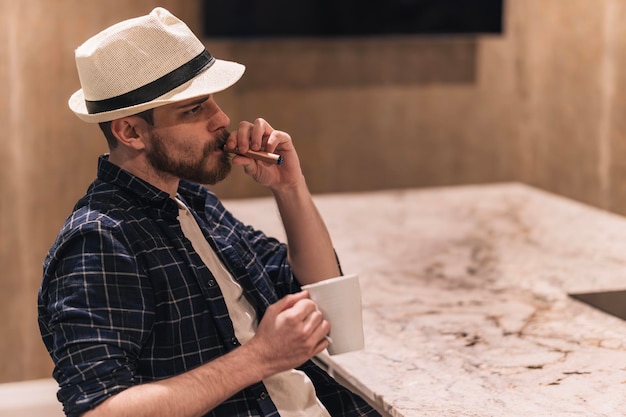 Nómada digital pensando en sus proyectos bebiendo café y fumando vape concepto de estilo de vida
