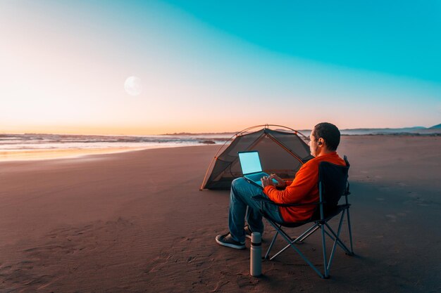 nômade digital sentado sozinho na beira da praia