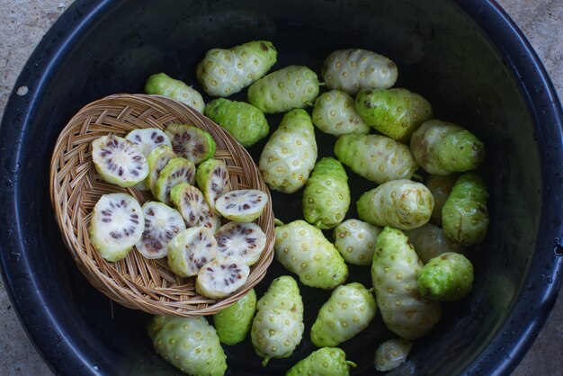 Noni fatia com noni fruta na bacia preta.