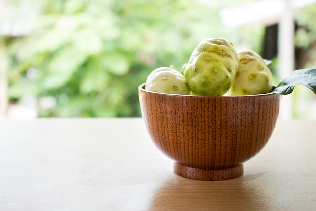 Noni ou Morinda citrifolia, excelente morinda, amoreira indiana, amoreira de praia ou fruta de queijo na mesa de madeira.