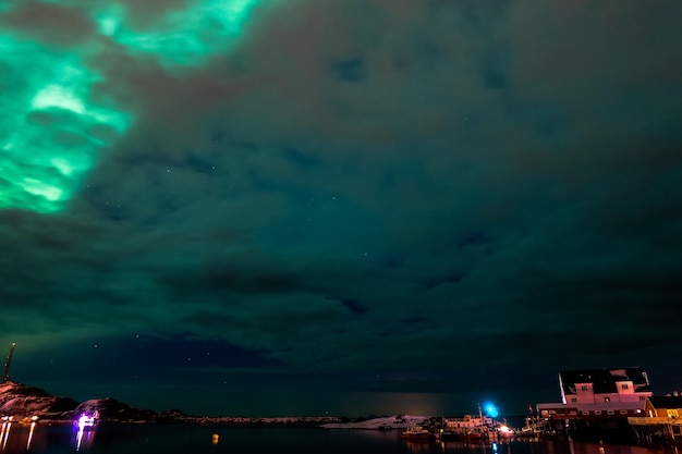 Nordlichter mit bewölktem Himmel über dem Dorf Tind auf den Lofoten