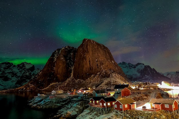 Nordlichter über den Bergen und Fischerhütten im Dorf Hamnoy auf den Lofoten