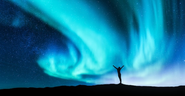 Foto nordlichter und silhouette der stehenden frau mit erhobenen armen