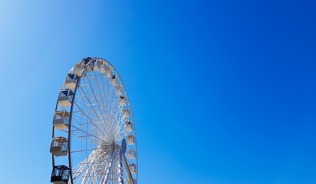 Noria grande blanca contra el cielo azul. Parte de la atracción sobre un fondo azul con espacio de copia. Cabañas, plataformas de observación.