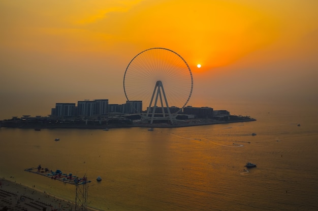 Noria de observación Dubai Eye Ferris durante la cálida puesta de sol naranja