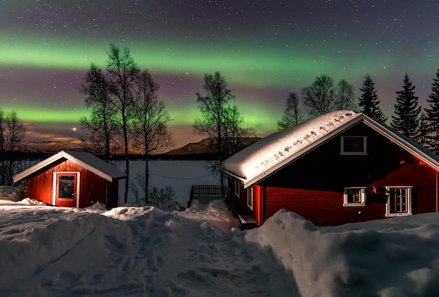 Northern Lights sobre el lago nevado congelado el granero y la casa de pesca Islas Lofoten Noruega