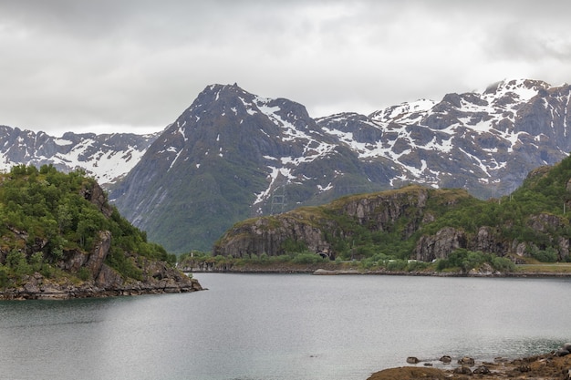 Norwegischer Fjord und Berge, umgeben von Wolken, Mitternachtssonne, Polartag, ideale Fjordreflexion in klarem Wasser