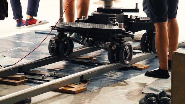 Nos bastidores da equipe de produção definindo a trilha dolly para equipamentos de câmera e gravação de vídeo 4K HD em um grande estúdio.