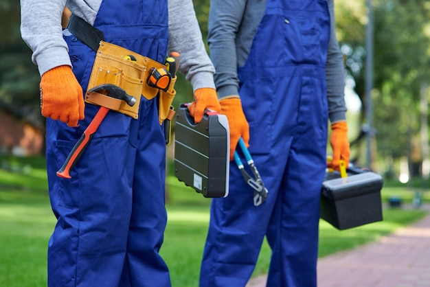 Nós podemos ajudar você. construtor masculino usando cinto de ferramentas carregando caixa de ferramentas no canteiro de obras