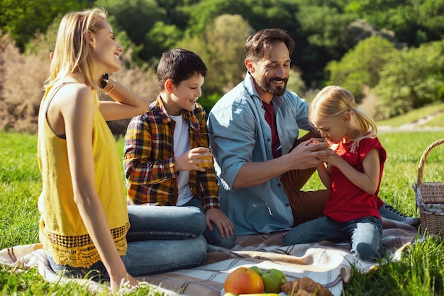 Nosso descanso juntos. Família amorosa encantada, passando um tempo juntos e fazendo piquenique