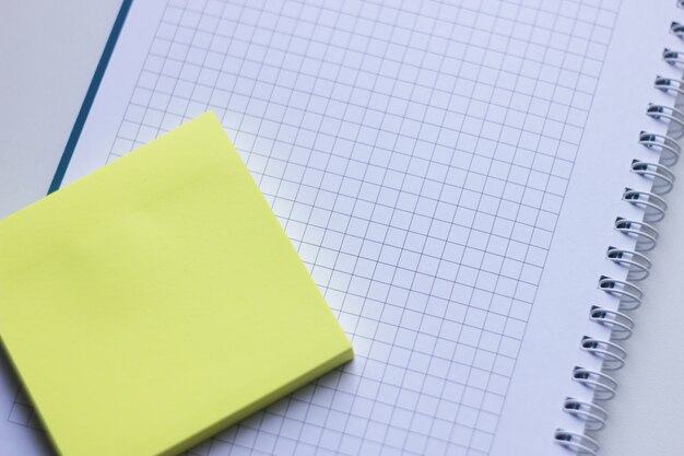 Nota adesiva amarela em branco em um caderno espiral de cima. Notas autocolantes removíveis.