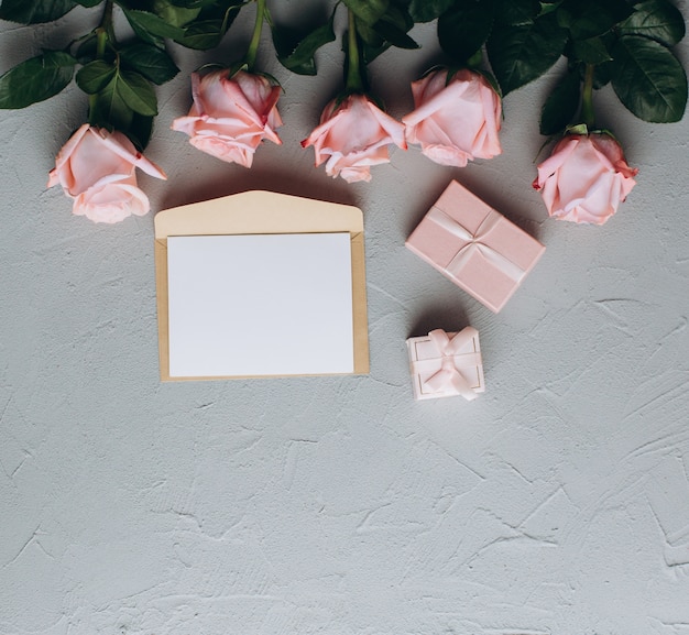 Foto nota de papel em branco com envelope, presentes e rosa-de-rosa