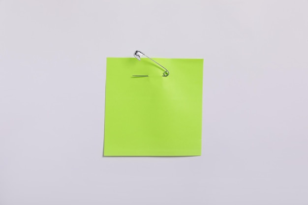 Foto nota de papel verde claro anexada com alfinete de segurança à vista superior do fundo branco