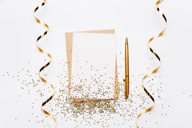 Foto nota em branco com envelope, fita, confete, caneta e estrelas de glitter dourados sobre fundo branco