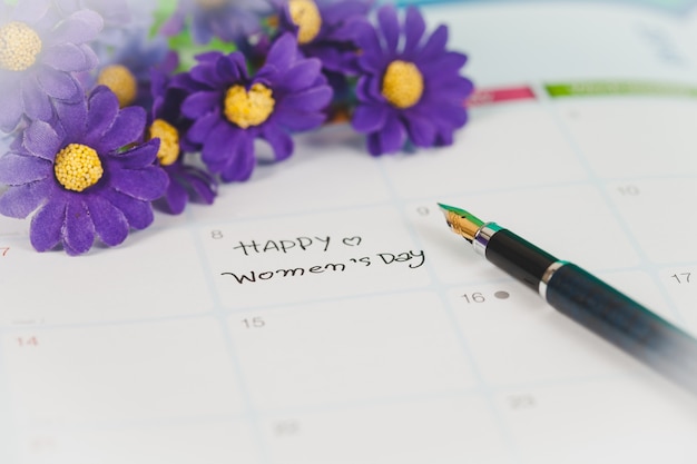 Nota feliz día de la mujer en el libro de calendario.