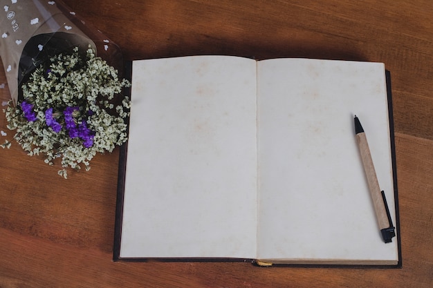 Nota de libro con la pluma en el fondo de madera de la tabla.