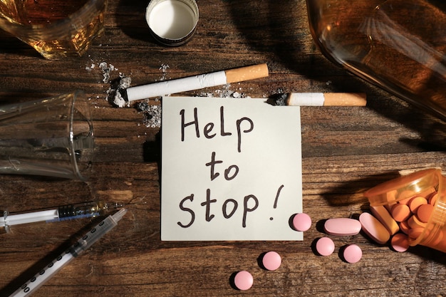 Nota con palabras Ayuda para detener las drogas alcohólicas y los cigarrillos en la mesa