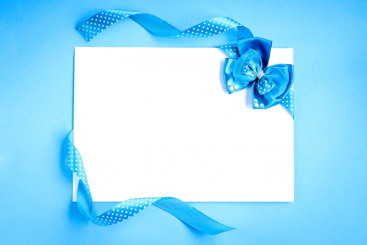 Foto nota de papel en blanco con cintas azules en lunares y arco sobre fondo azul.