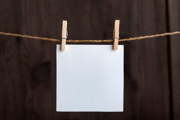 Foto notas en blanco blancas que cuelgan con pinzas para la ropa en una cuerda sobre la superficie de madera. copie el espacio. espacio para tu texto.