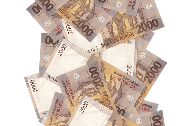 Foto notas de 2000 rupias da indonésia voando isoladas no branco. muitas notas caindo com espaço de cópia em branco no lado esquerdo e direito