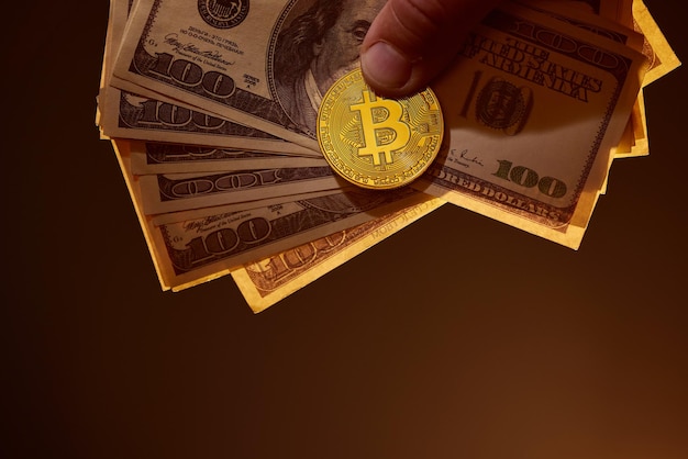 Notas de bitcoin e dólar americano nas mãos em uma troca de dinheiro eletrônico de fundo escuro quente
