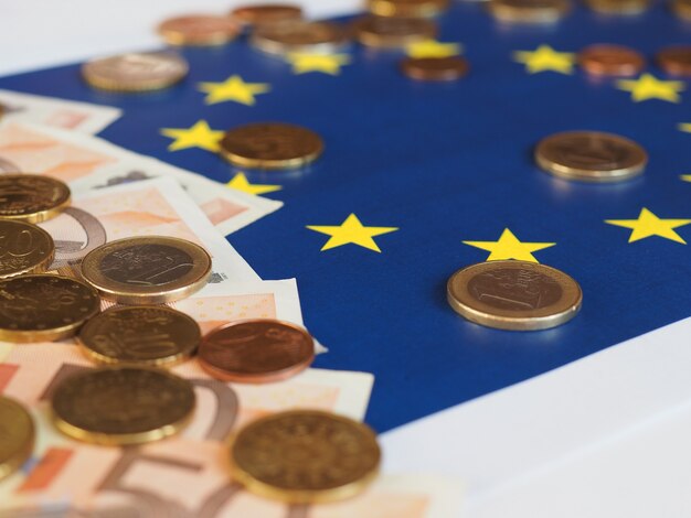 Notas e moedas de euro (eur), moeda da união europeia sobre a bandeira da europa