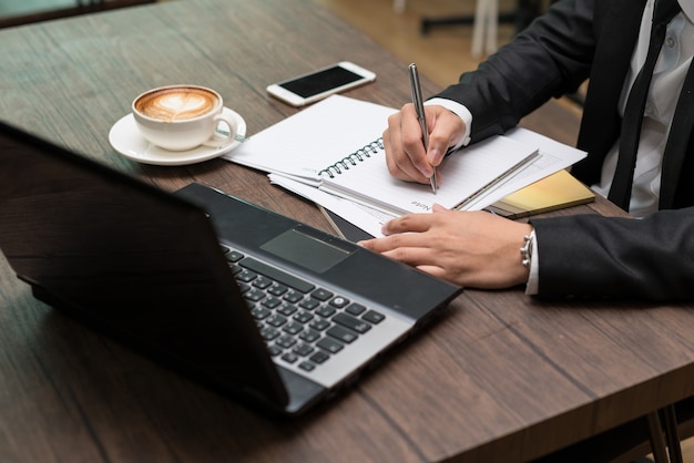 Notas de la escritura joven empresario asiático sentado en una cafetería